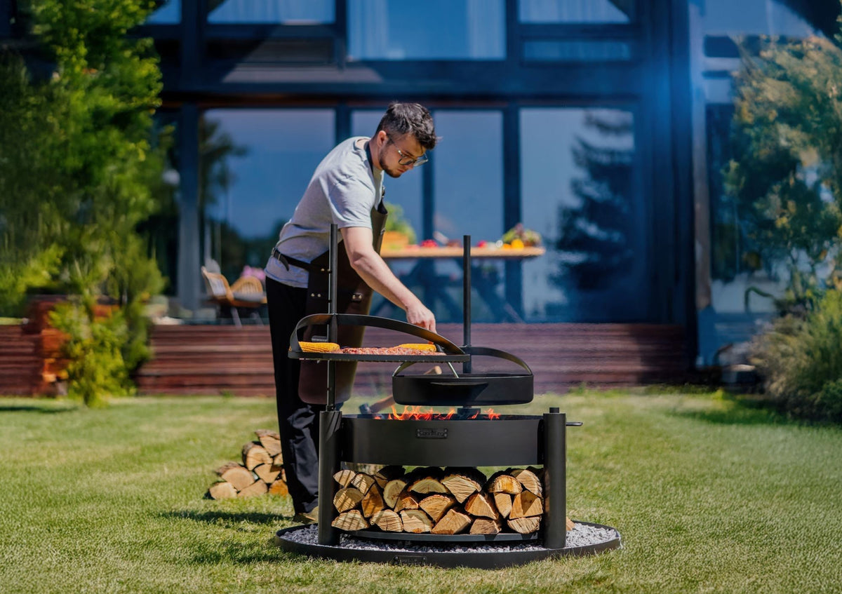 Cook King – Pack Brasero de jardin multifonction « MONTANA X » 80 cm avec grille de cuisson 60 cm, mât supplémentaire et poêle en acier brut 50 cm — mise en situation