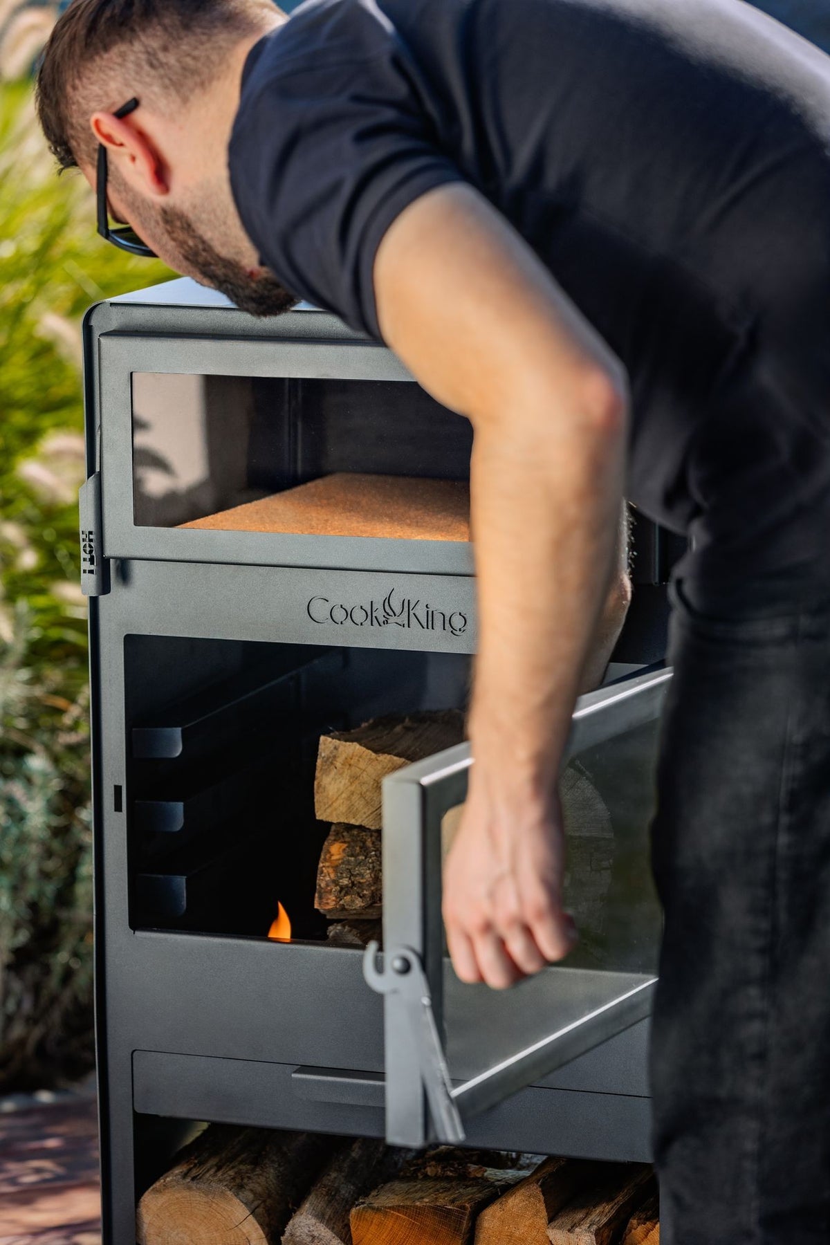 Cook King – Pack VENTO – Brasero cheminée avec four, grille de cuisson et range-bûches — mise en situation