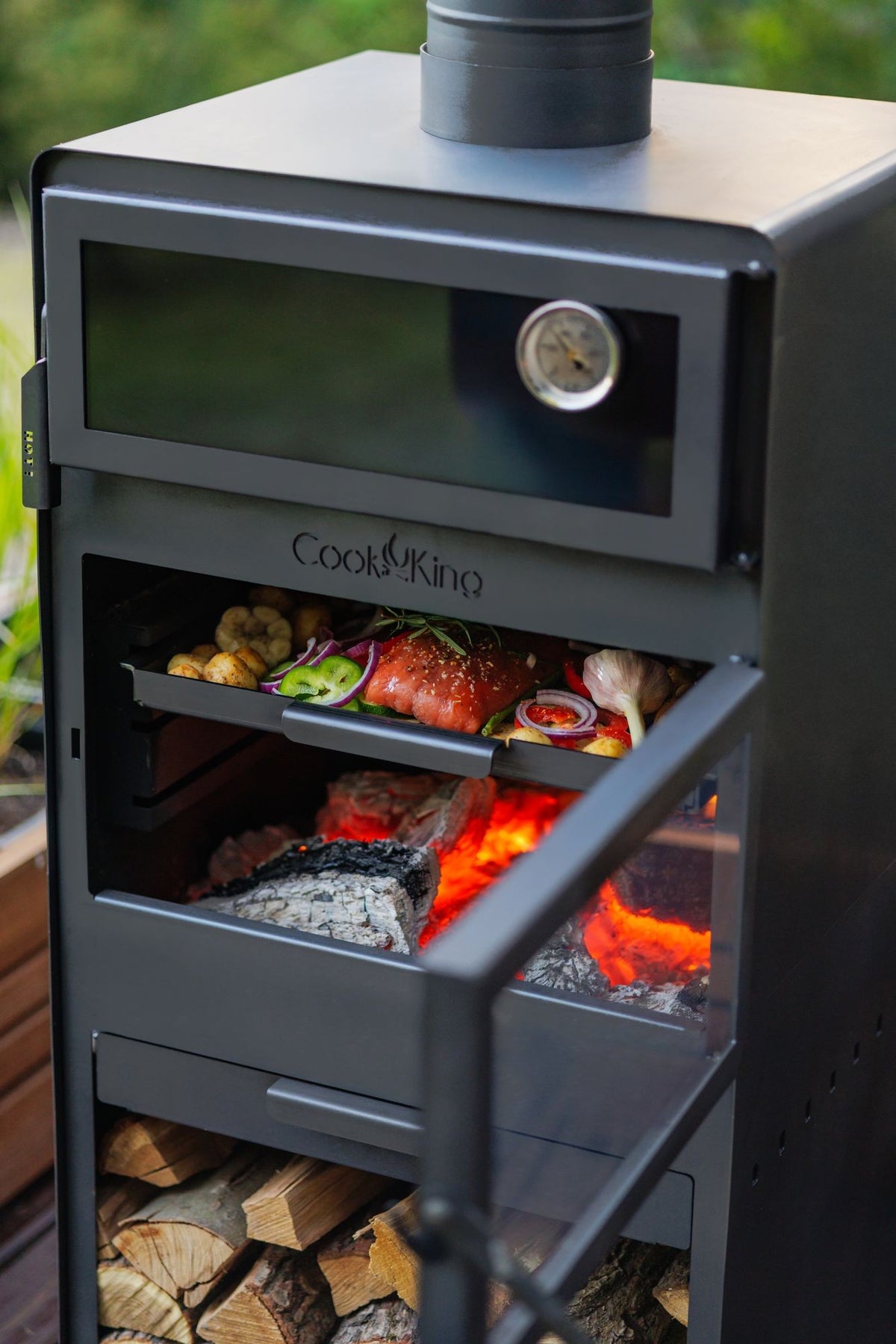 Cook King – Pack VENTO – Brasero cheminée avec four, grille de cuisson et range-bûches — mise en situation