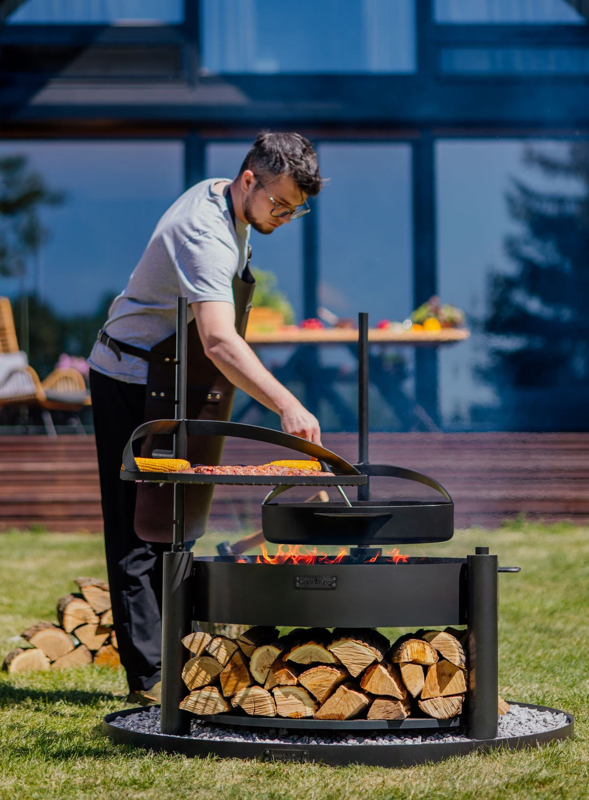Cook King – Pack Brasero de jardin multifonction « MONTANA X » 80 cm avec grille de cuisson 60 cm, mât supplémentaire et poêle en acier brut 50 cm — mise en situation