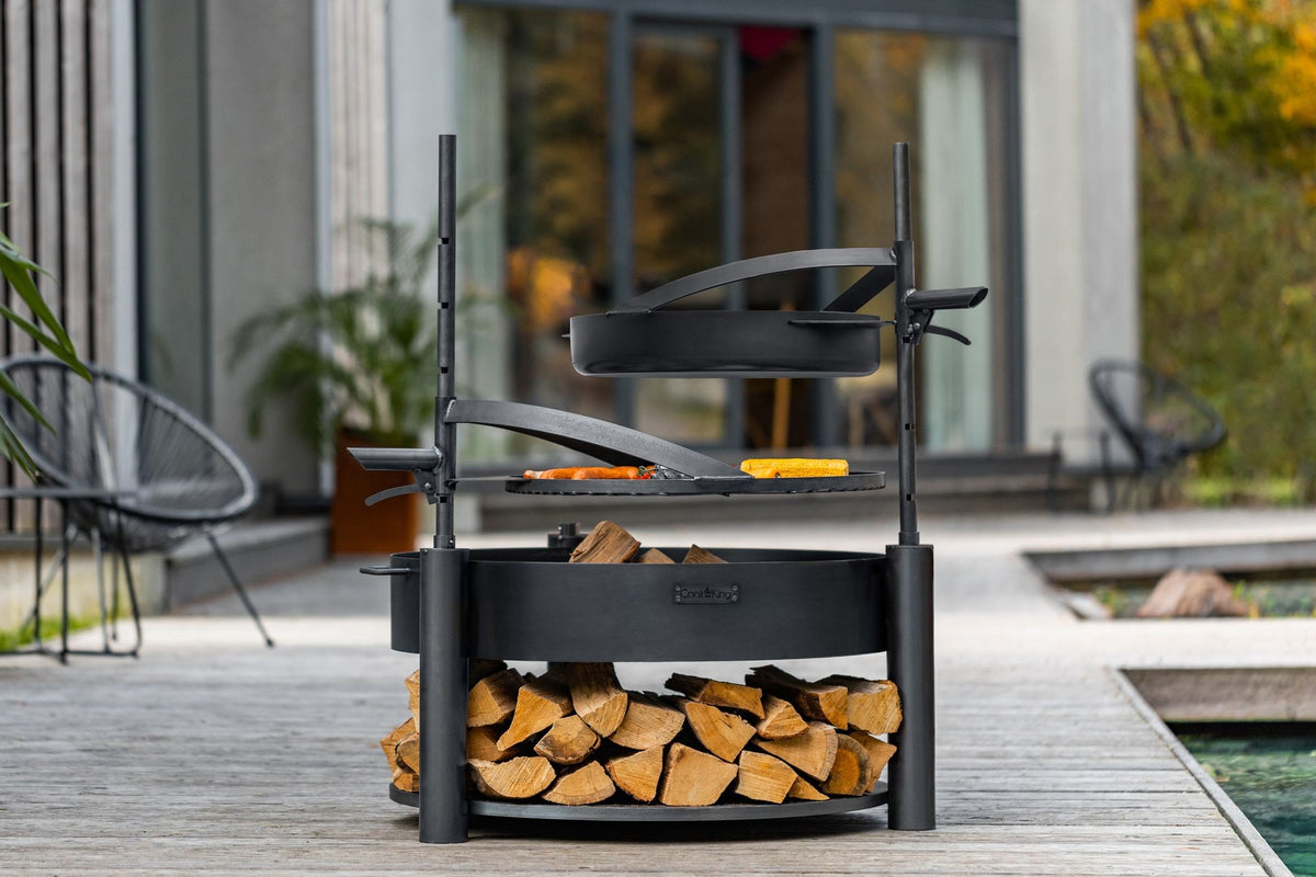 Cook King – Pack Brasero de jardin multifonction « MONTANA X » 80 cm avec grille de cuisson 60 cm, mât supplémentaire et poêle en acier brut 50 cm — mise en situation