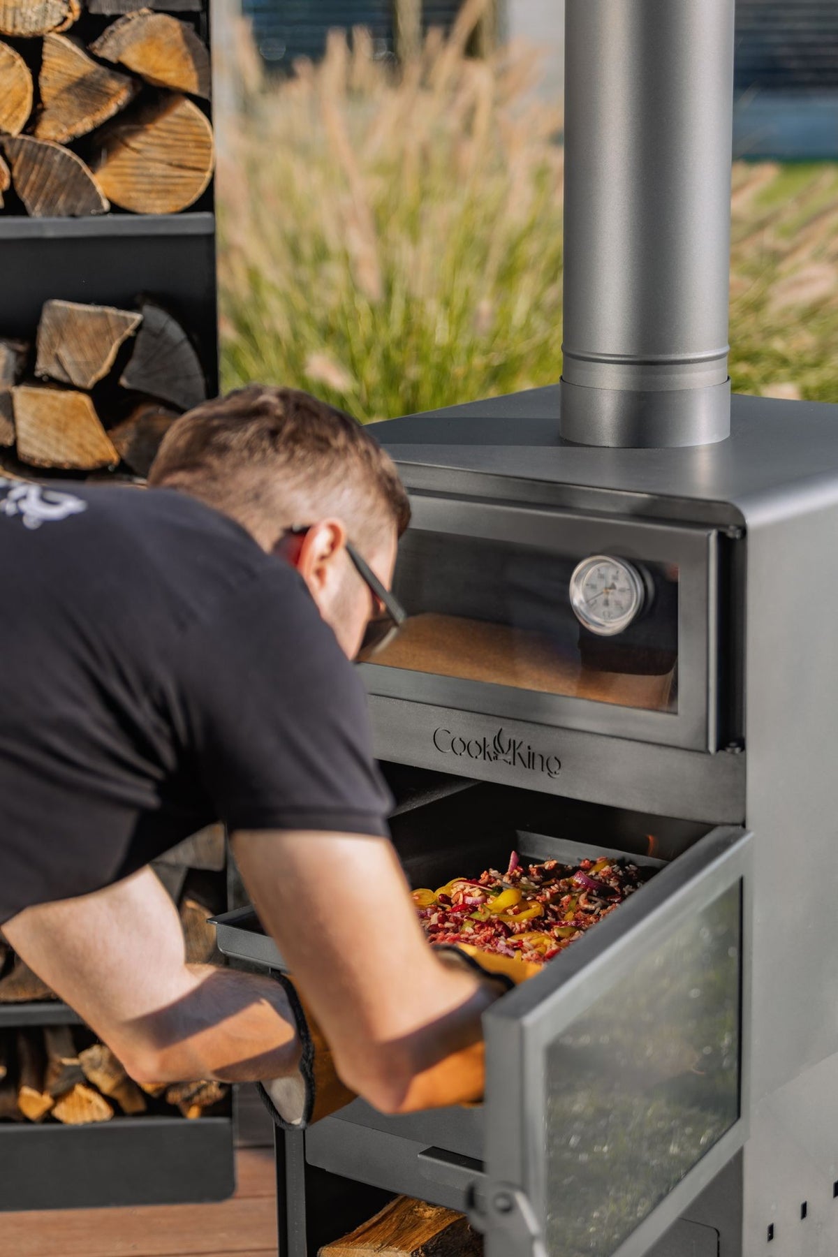 Cook King – Pack VENTO – Brasero cheminée avec four, grille de cuisson et range-bûches — mise en situation