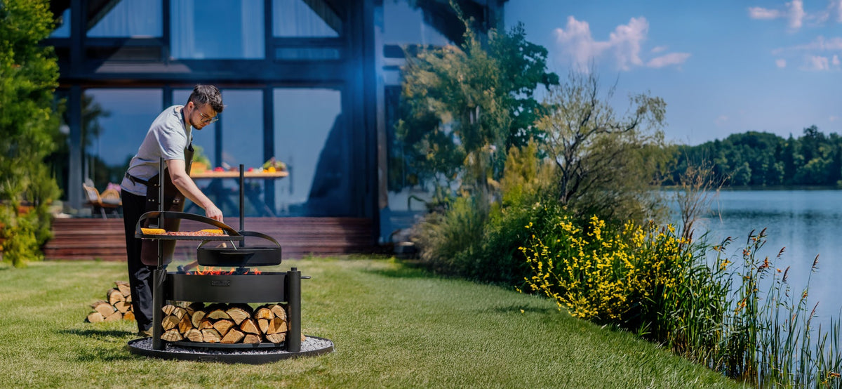 Cook King – Pack Brasero de jardin multifonction « MONTANA X » 80 cm avec grille de cuisson 60 cm, mât supplémentaire et poêle en acier brut 50 cm — mise en situation